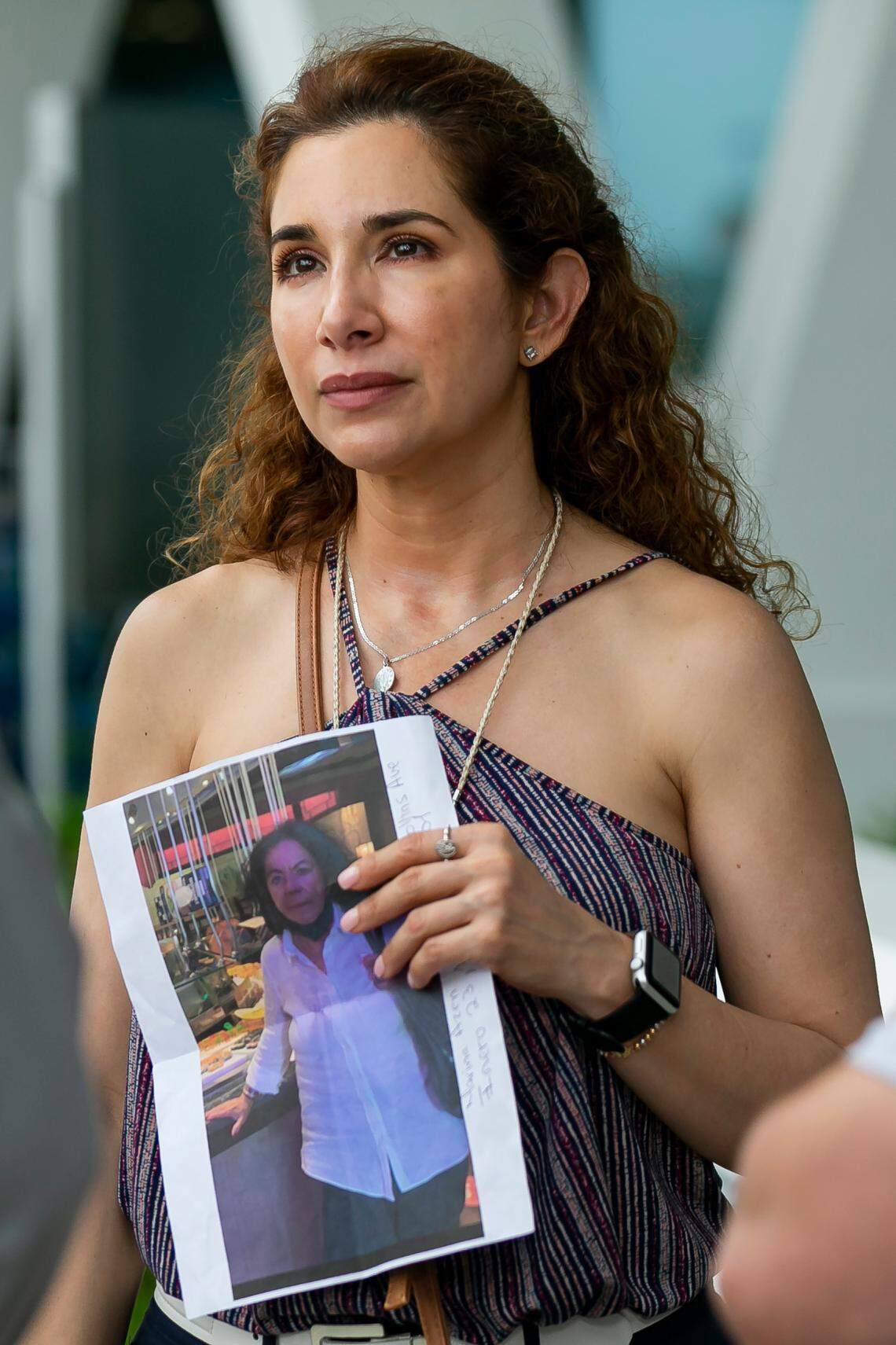 Luz Marina Peña holds a photo of a loved one as she waits for updates at the reunification center at 9301 Collins Ave in Surfside, Florida, on Thursday, June 24, 2021. A part of the Champlain Towers South Condo at 8777 Collins Ave. collapsed early Thursday.