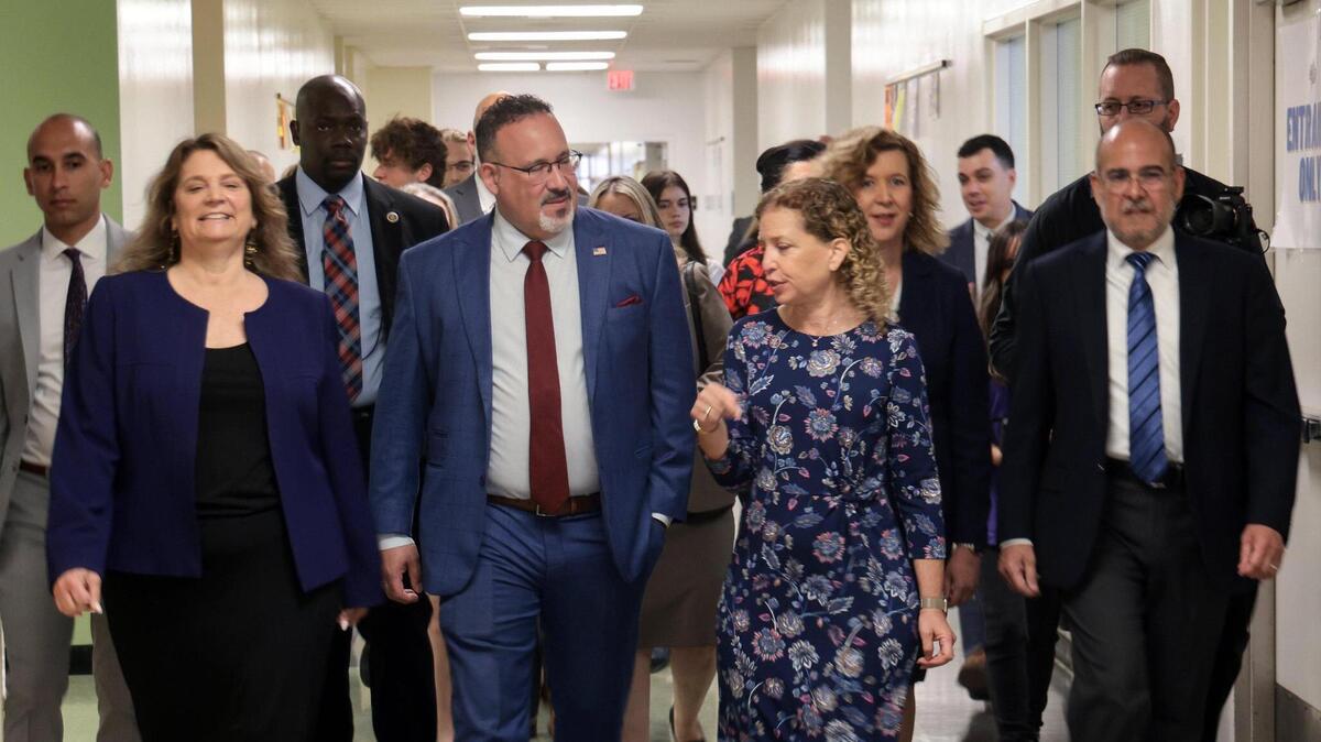 El secretario de Educación federal Miguel Cardona (centro)  y la representante federal Debbie Wasserman Schultz conversan mientras recorren la secundaria Cypress Bay en Weston, Florida,  el 4 de abril de 2020.