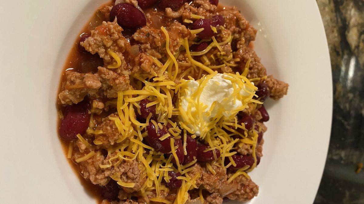Grated cheese and sour cream complete this chili meal.