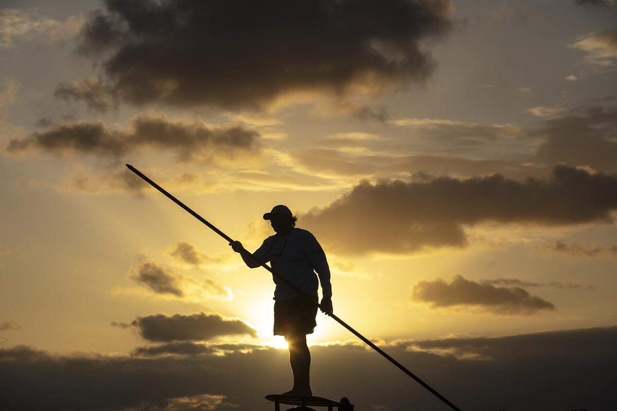 Islamorada, Florida: Florida Keys Fishing Captain Tim Klein directs a fly fishing client to fish off of Islamorada as the sun rises over Florida Bay.