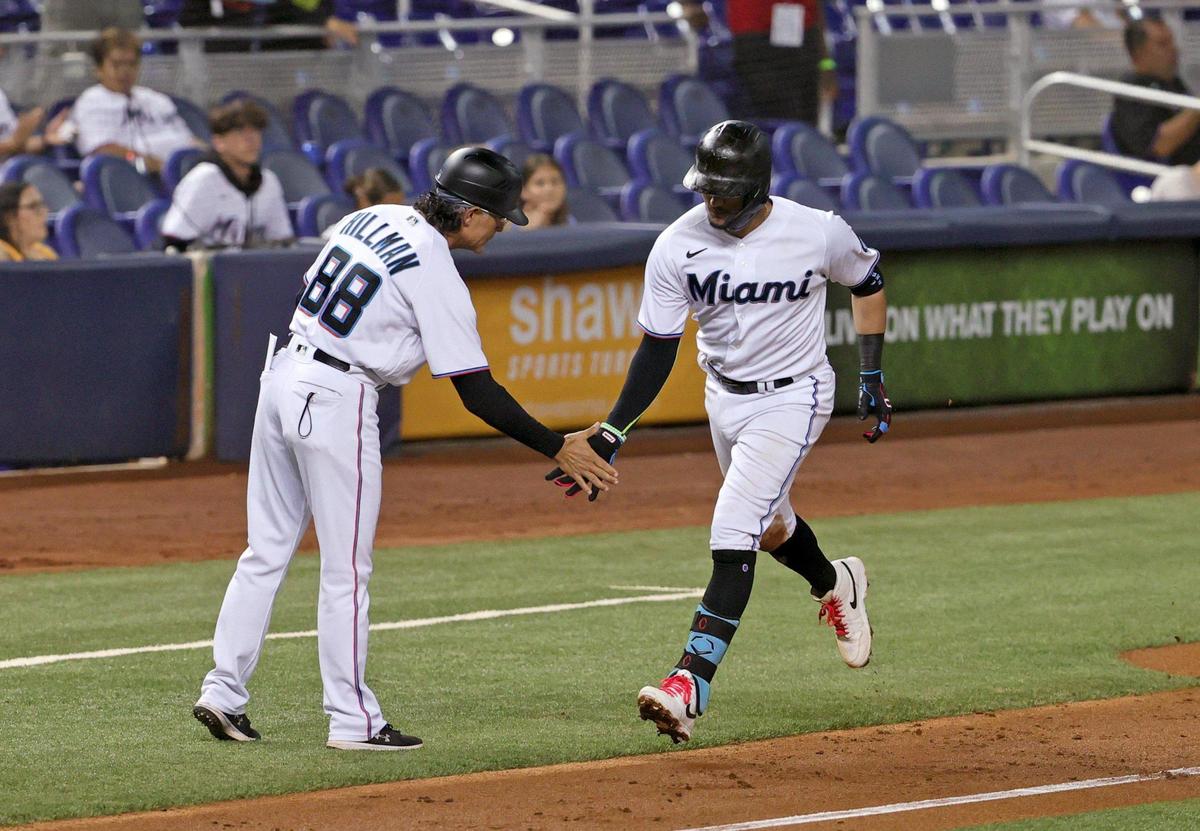 Miami Marlins shortstop Miguel Rojas (19) is congratulated by Marlins third base coach Trey Hillman (88) after hitting a two runs hone run during the second inning of their baseball game against the Washington Nationals at loanDepot park on Thursday, August 26, 2021 in Miami, Florida.