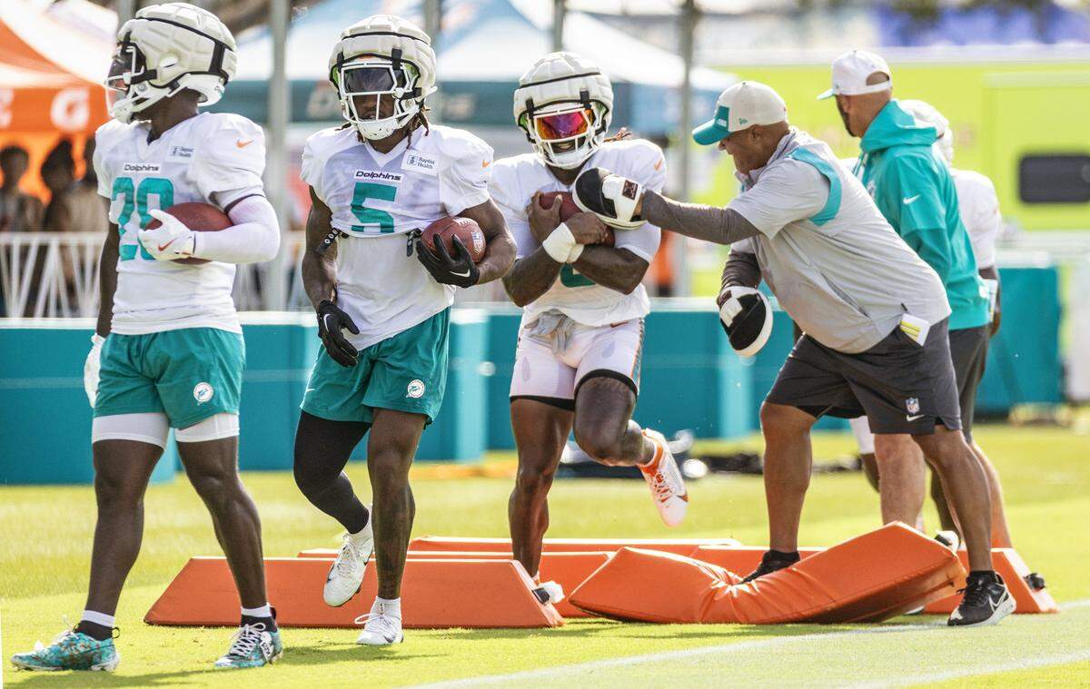Miami Dolphins running backs De'Von Achane (28), Jaylen Wright (5) and Alexander Mattison (8) run through practice drills.