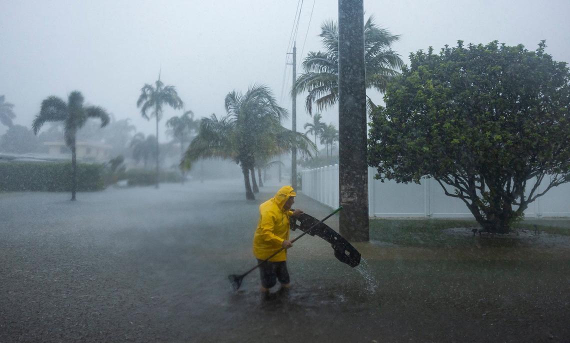 A man works to clear debris from a flooded street on the corner of Garfield Street and 14h Avenue as heavy rain floods the nearby neighborhood on Wednesday, June 12, 2024, in Hollywood, Fla.