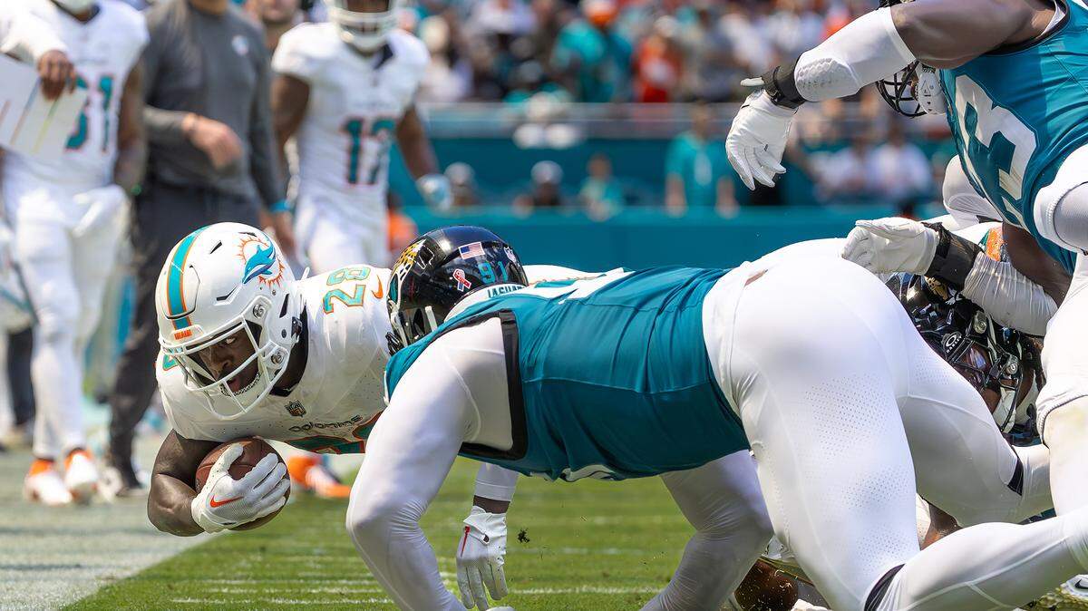 Miami Dolphins running back De’Von Achane (28) dives for a first down as Jacksonville Jaguars defensive end Arik Armstead (91) defends during the first half of an NFL football game at Hard Rock Stadium on Sunday, Sep. 8, 2024, in Miami Gardens, Fl.