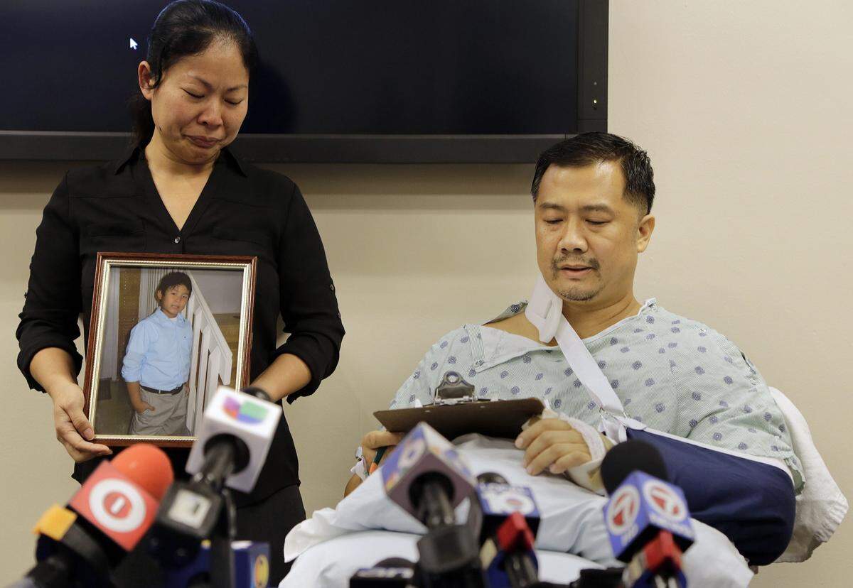 Hai Nam Vu, right, along with his wife, Lynn Ma, holding a photo of their son, Aaron Vu, speaks at his press conference from Ryder Trauma Center after learning of his son’s death as he recuperates from a gunshot wound to his shoulder on Tuesday, Nov. 26, 2013.