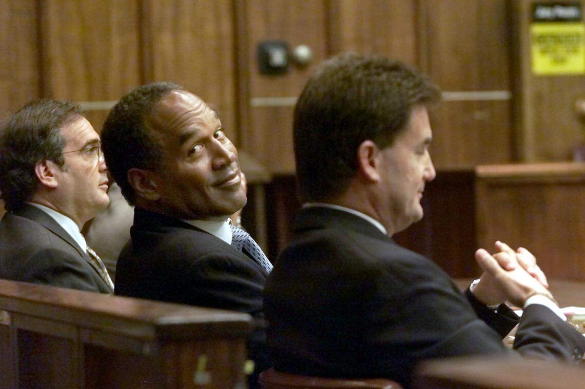 O.J. Simpson, center, looks back at some students in the courtroom as he sits with his attorneys Yale Galanter, right, and Lee Cohn, left, in Miami circuit court Wednesday, Oct. 10, 2001 in Miami.
