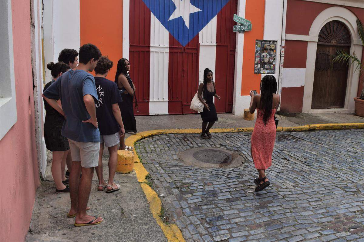 Tourists wait to get their picture taken in front of the Puerto Rican flag in Old San Juan. The U.S. territory has decreed a curfew and ordered all non-essential businesses to close.