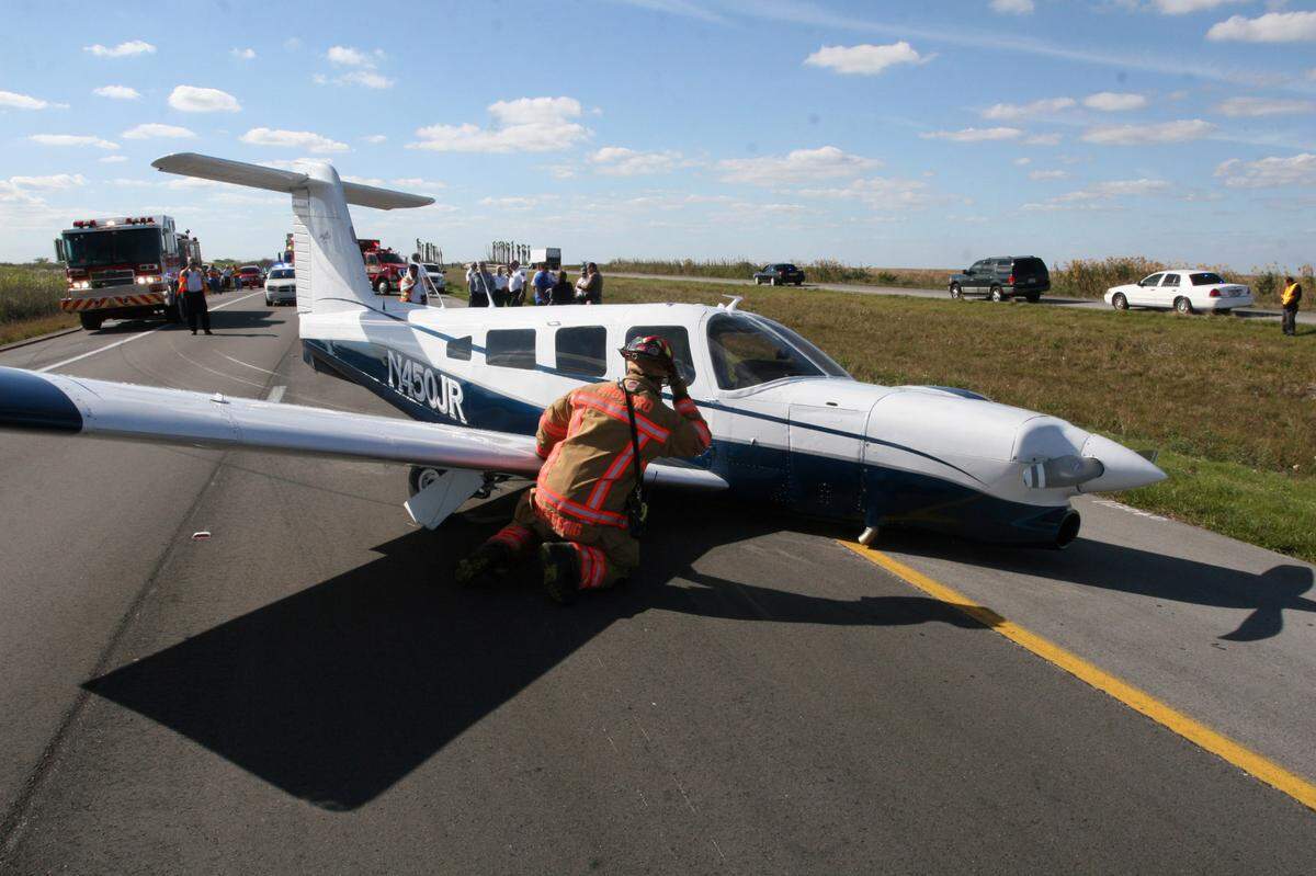 Broward Sheriff Fire Rescue Lt. Herb Schosnig checks for hazards after a Piper single engine plane made an emergency landing on Interstate 75 on Jan. 28, 2010. The male pilot and a female passenger were en route to Opa-locka Executive Airport from Colombia, Tennessee. The pilot told Broward Sheriff Firefighters that he had engine issues and had to land the plane. BSFR Regional Everglades units were on scene within four minutes of the 911 call. The uninjured couple was en route to Miami for a 5 p.m. cruise when they encountered trouble. The Florida Highway Patrol reports that one lane of I-75 southbound remains open as the Federal Aviation Administration conducts their on scene investigation. The single-engine Piper PA-32, which has six seats, landed on its belly, with the right landing gear bent.