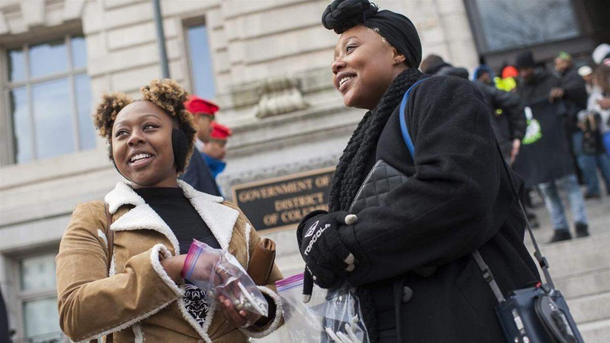 Sisters Jackie, left, and Bria Cook hand out marijuana cigarettes at a rally in Washington, D.C., to push for changes to the District’s medical cannabis law. Minority legalization advocates have raised concerns that they won’t have an equitable stake in the emerging business.