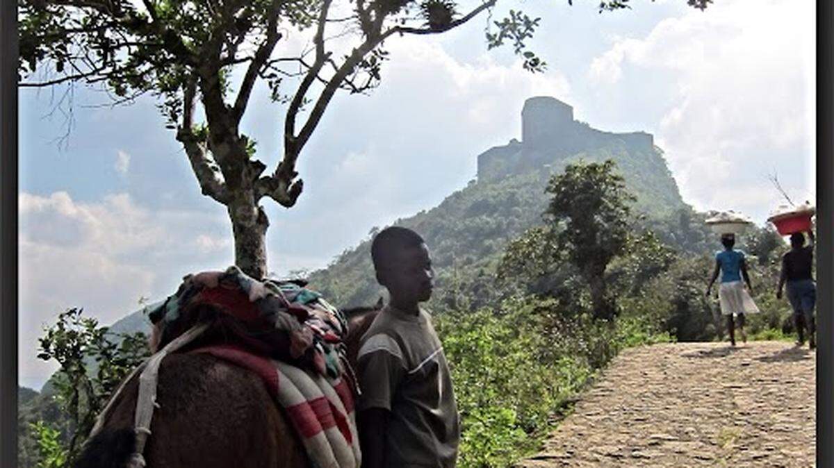 Un niño se detiene brevemente en su ascenso en la escarpada montaña de la ciudad de Milot, en el norte de Haití, donde se ve al fondo la fortaleza Citadelle Henry. La famosa fortaleza posee una de las mayores colecciones de cañones del mundo, anterior a la fundación de Haití como nación en 1804.