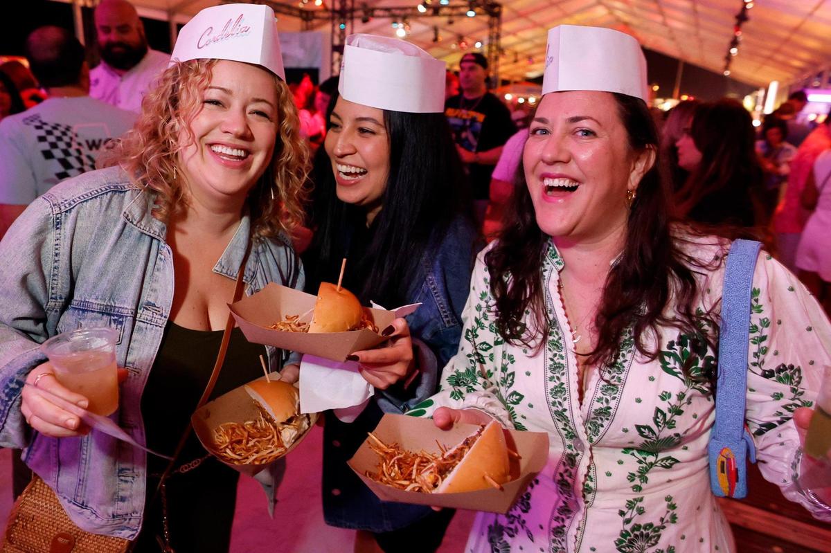Anne Lischwe, Jackie Gomez and Victoria Probert sample burgers at 2025 Burger Bash during the South Beach Wine & Food Festival in Miami Beach.