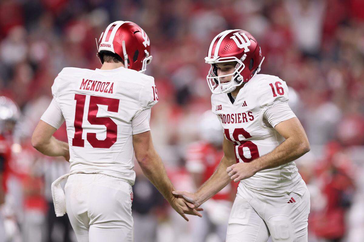 INDIANAPOLIS, INDIANA - DECEMBER 06: Fernando Mendoza #15 of the Indiana Hoosiers high fives teammate Alberto Mendoza #16 as he runs onto the field against the Ohio State Buckeyes during the first quarter in the 2025 Big Ten Football Championship at Lucas Oil Stadium on December 06, 2025 in Indianapolis, Indiana.  (Photo by Michael Reaves/Getty Images)