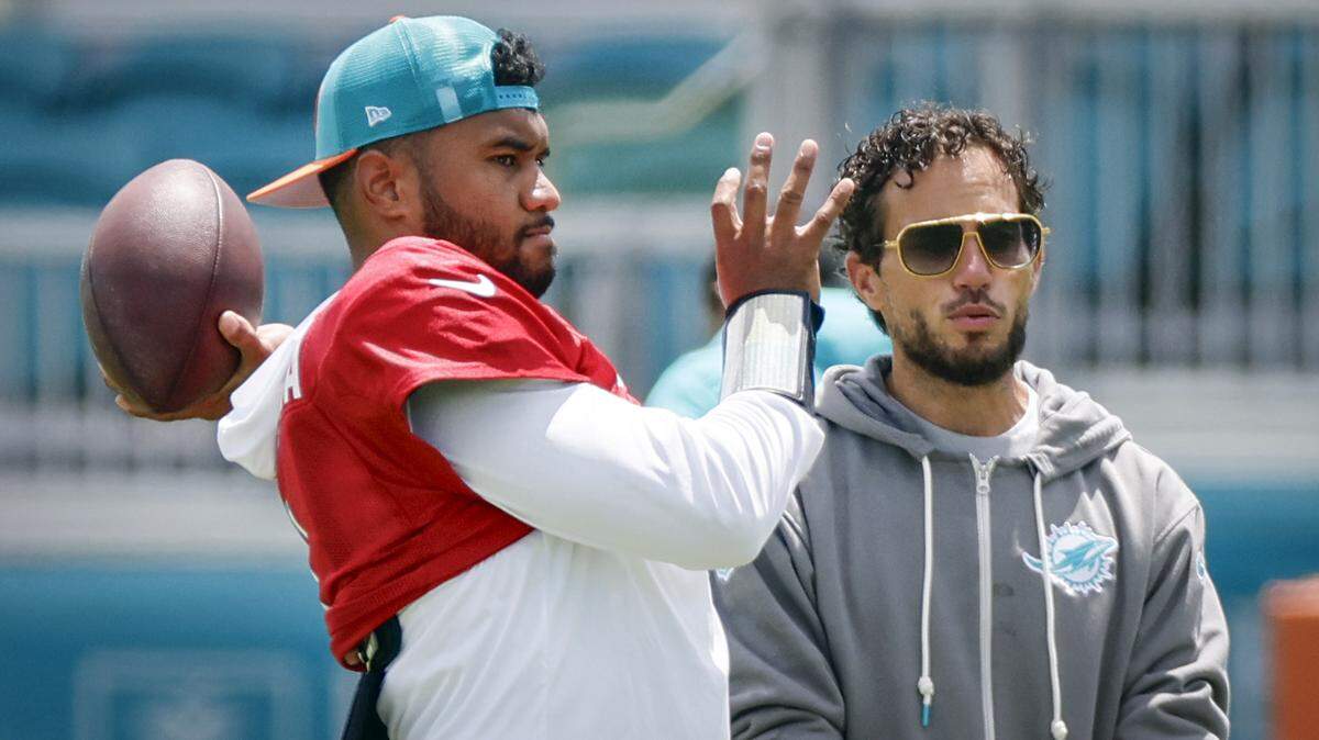 Miami Dolphins quarterback Tua Tagovailoa (1) sets up to pass as head coach Mike McDaniel watches during practice at Baptist Health Training Complex in Miami Gardens, Florida, on Thursday, September 5, 2024.