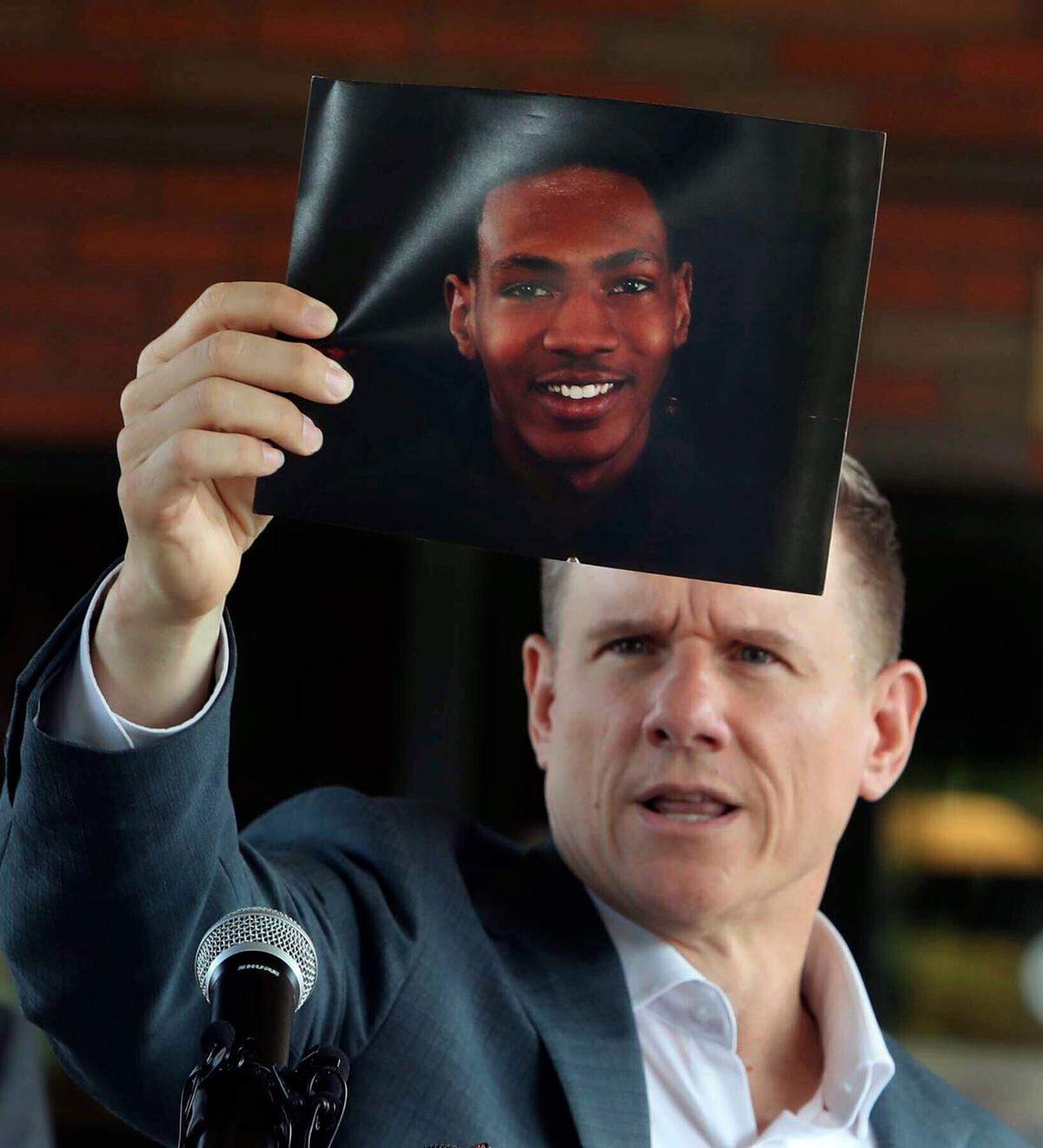 Attorney Bobby DiCello, representing the family of Jayland Walker, holds up a photograph of Walker before he and his legal team give their statements after the City of Akron’s news conference at the Firestone Park Community Center on Sunday, July 3, 2022, in Akron, Ohio, where body cam video was shown of the police shooting of Walker almost a week earlier. (Karen Schiely/Akron Beacon Journal via AP)