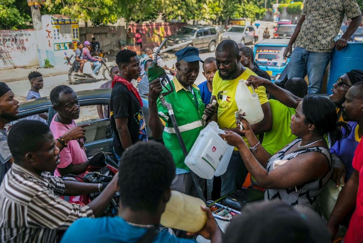 People crowd around a gas pump as they try to get their gas tanks filled at a gas station in Port-au-Prince, Haiti, Saturday, Nov. 12, 2022. Whoops of excitement echoed through the streets of Port-au-Prince early Saturday as gas stations opened across Haiti for the first time in two months after a powerful gang lifted a crippling fuel blockade.