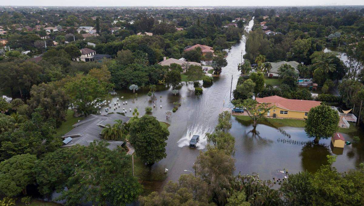 A car drives through a flooded street in a residential neighborhood in Plantation, Florida, on Monday, Nov. 9, 2020. Tropical Storm Eta made its way past South Florida Sunday night, leaving roads and neighborhoods flooded.