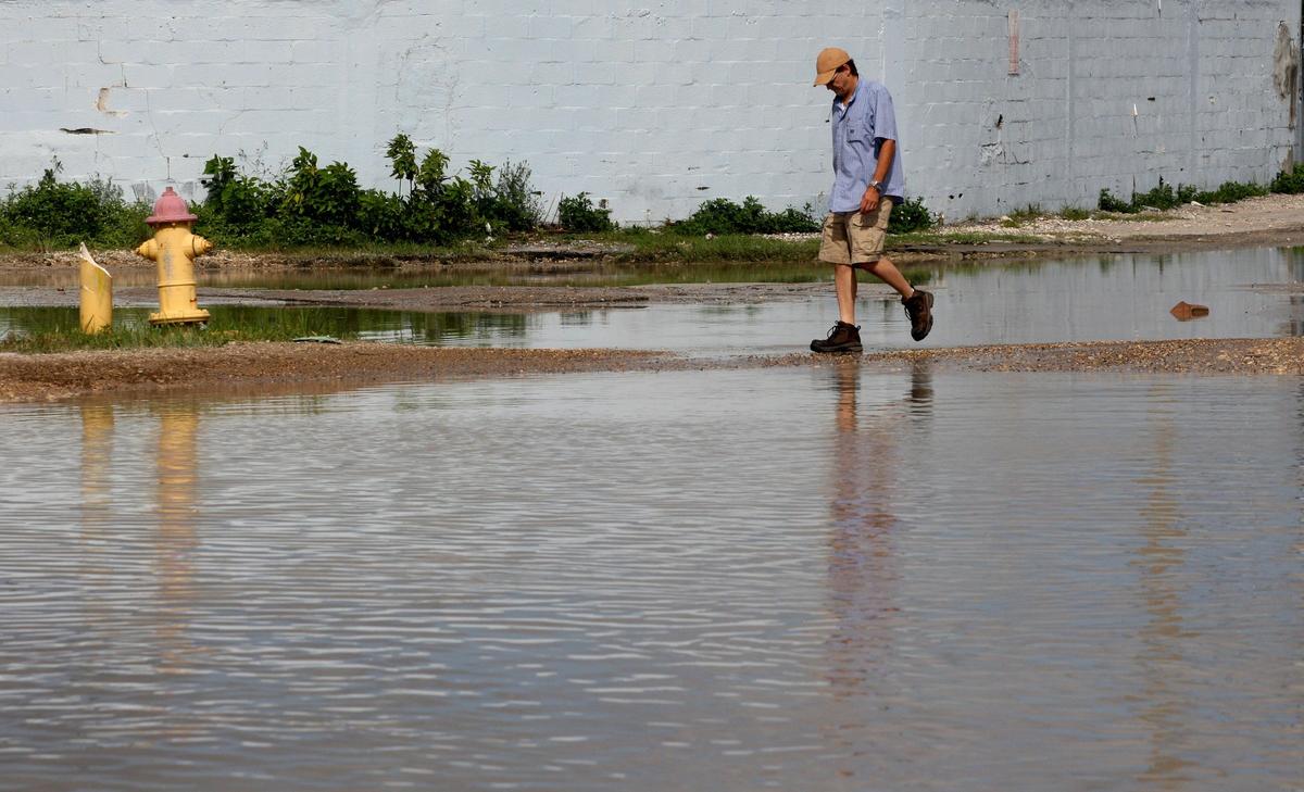 The streets surrounding an Opa-locka industrial zone flood every time it rains due to an old and clogged drainage system as trucks, cars, and people try to navigate through the contaminated water on Sept. 4, 2018.