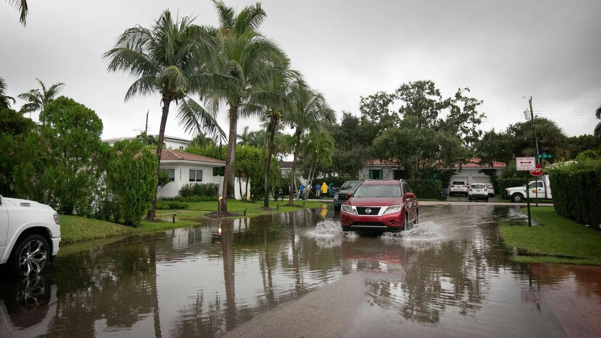 Un auto circulando hacia el norte por Northeast 10 Place, cerca de Northeast 105 Street, donde las vías se inundan con frecuencia durante la marea alta. Obras Públicas de Miami Shores estaba en la zona limpiando los desagües y bombeando el agua de la inundación de las calles.