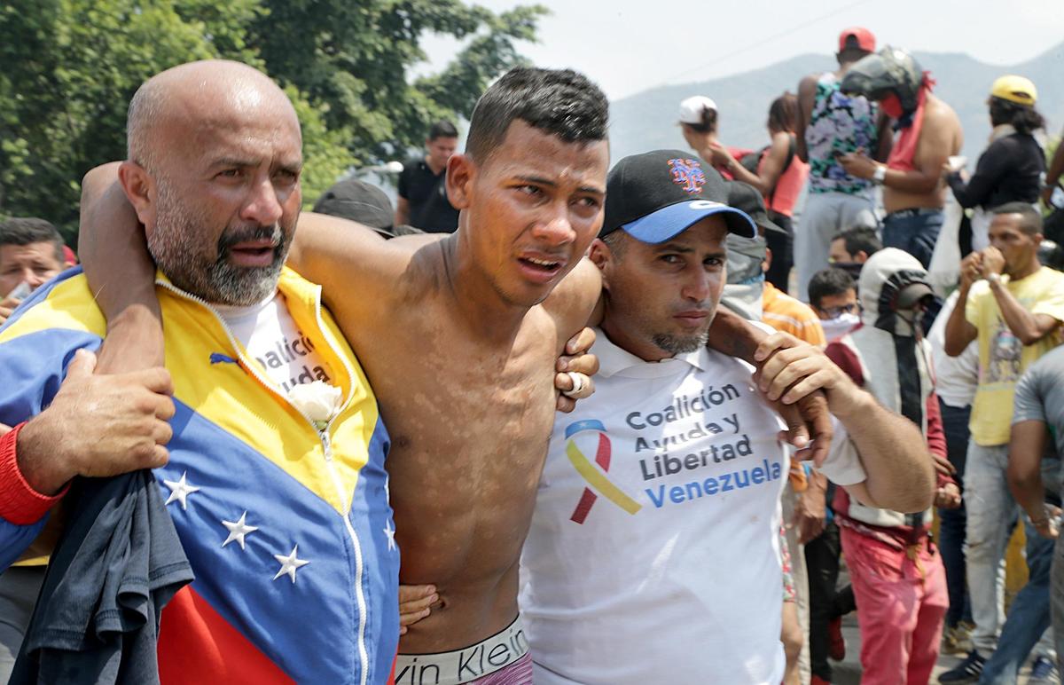 Protesters help a colleague who got affected by tear gas on the Colombian side of the border as they get attacked by the Maduro’s military and members of los Colectivos, while attempting to move in several trucks loaded with aid donated for their country through the Simon Bolivar International bridge on the Colombian side as interim President Juan Guaido Guaido and his supporters were hoping to move humanitarian aid into Venezuela Saturday against the wishes of leader Nicolas Maduro on February 23, 2019.