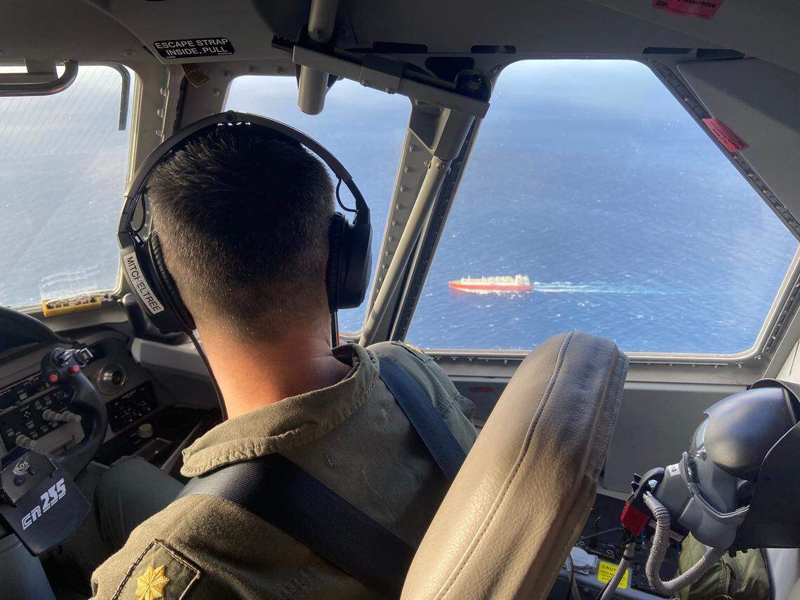 U.S. Coast Guard pilot Lt. Cmdr. Joshua Mitcheltree flies a C-144 Ocean Sentry above the Florida Straits Saturday, Jan. 14, 2023, as a cargo ship sails on the water below.