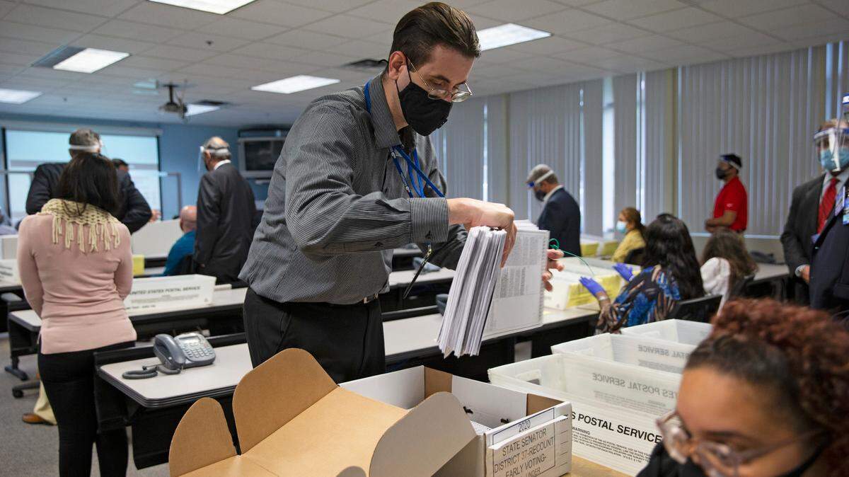 Un empleado del Departamento de Elecciones de Miami-Dade Evacía una caja con boletas que serían inspeccionadas por el empleado electoral y observadores de campaña durante un recuento manual para el Distrito 37 del Senado entre la republicana Ileana García y el demócrata José Javier Rodríguez, en una imagen de 12 de noviembre de 2020, en Miami, Florida.
