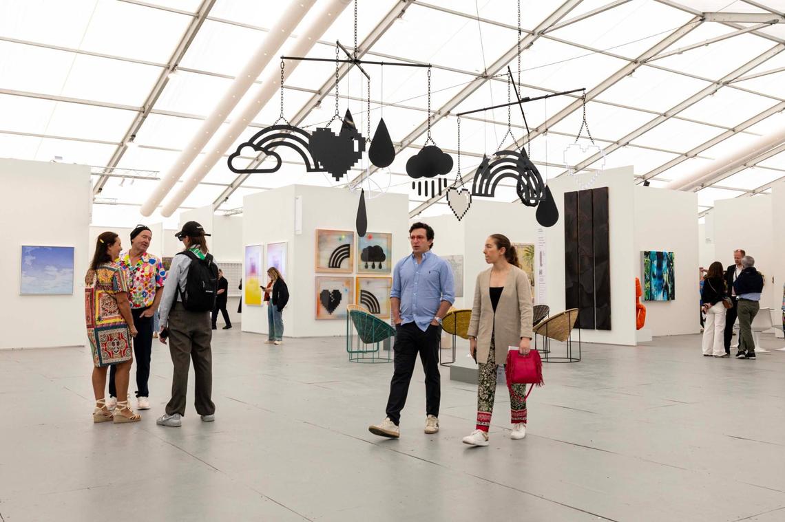 Guests walk underneath “Highs and Lows (Double Happiness)” by Wendy White at Untitled Art Fair for Art Week on Tuesday, Dec. 3, 2024, in Miami Beach, Fla