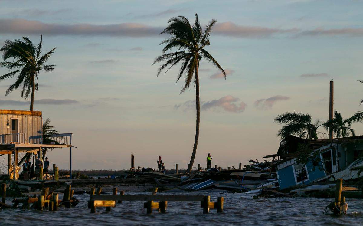 People are seen near damaged properties on a broken section of Pine Island Road on Thursday, Sept. 29, 2022, in Matlacha, Fla. Hurricane Ian made landfall on the coast of South West Florida as a category 4 storm Tuesday afternoon leaving areas affected with flooded streets, downed trees and scattered debris.