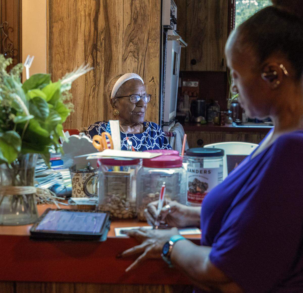 Thelma Vernell Anderson Gibson, left, the cherished icon of Coconut Grove, is celebrating her 99th birthday this month and continues to be steward of beyond the Grove as she is photographed in her kitchen of her home where she has a view of family photos and other memorabilia as while her niece Alvetia Anderson, right, stop by for a visit on Tuesday, December 10, 2025, in Miami, Florida. Gibson's groundbreaking contributions to the community as a dedicated educator and an advocate for civil rights, Gibson played a vital role in promoting social justice and equality. She was instrumental in establishing programs that empowered youth and fostered cultural awareness. Her legacy is marked by her unwavering commitment to uplifting her community, making her a beloved figure whose impact continues to inspire future generations.