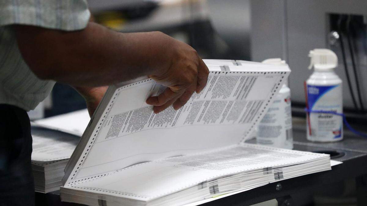 A Broward County Elections staffer prepares to load a machine as they count ballots in the November 2018 recount.