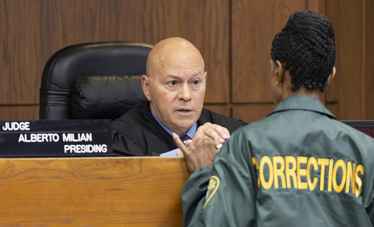 Miami-Dade Circuit Judge Alberto Milian talks with a corrections officer at the Richard E. Gerstein Justice Building on Thursday, Aug. 14, 2025, in Miami, Fla. Milian has overseen the case of Oscar Olea, a former Key Biscayne gymnastics coach who allegedly sexually abused his students.