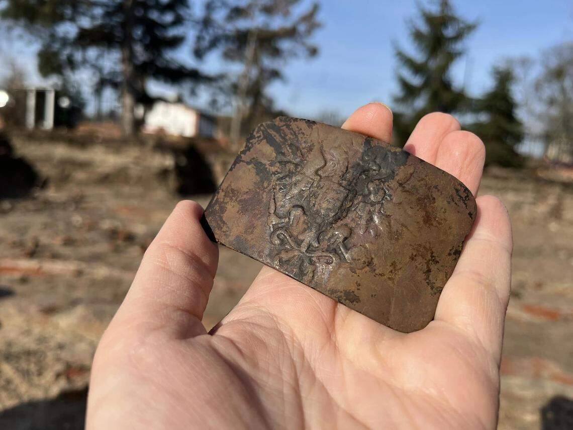 An ornately decorated belt buckle found in the debris.