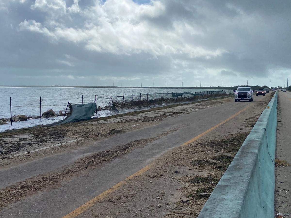 Fencing is blown out and seaweed strewn on the roadway of the 18 Mile Stretch of U.S. 1 in the Florida Keys Thursday, Nov. 16, 2023.