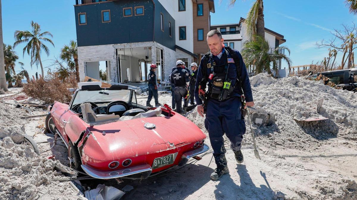 Un miembro del Grupo de Trabajo 2 de Búsqueda y Rescate Urbano de la Florida pasa junto a un Corvette de 1965 dañado por las aguas del huracán Ian en Fort Myers Beach el lunes.