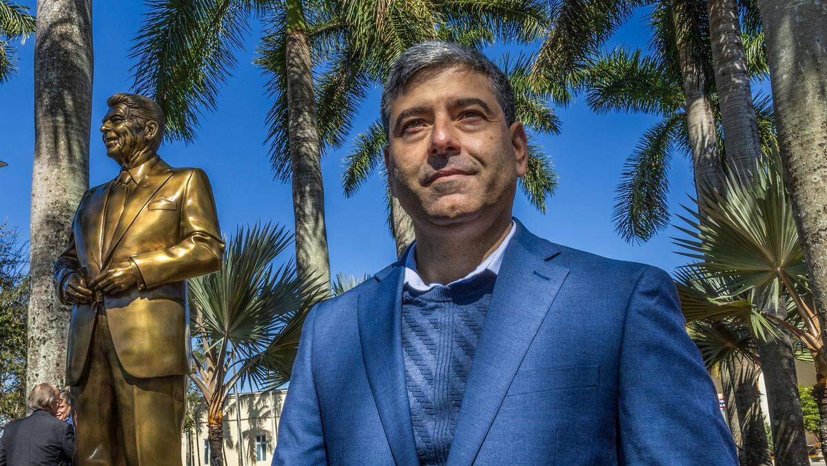 Cuban American artist Carlos Enrique Prado posed by his sculpture of former President Ronald Reagan, during the unveiling ceremony at Florida International University, on Feb. 6, 2026 