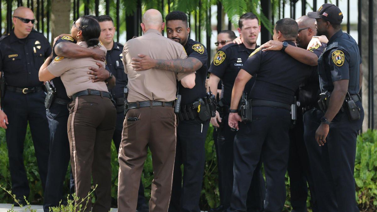 Policías de Miami-Dade y de North Miami se consuelan mutuamente después de escolar los restos del detective César Echaverry desde el Hospital Jackson Memorial Hospital hacia Medicina Legal, el 19 de agosto de 2022.