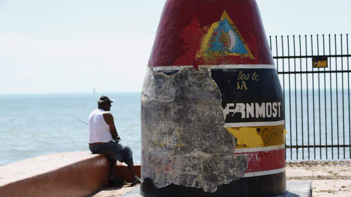 A man fishes next to the Southernmost Point Buoy damaged by Hurricane Irma, Wednesday, Sept. 13, 2017, in Key West.