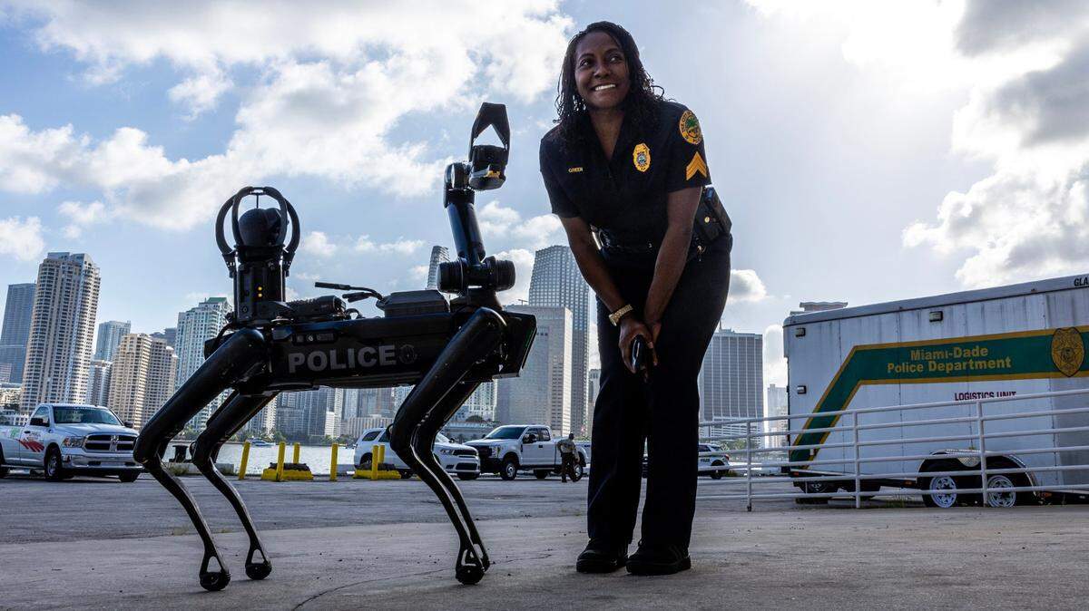 City of Miami Police officer Green poses next to “Spot,” a robotic dog owned by Miami-Dade Police’s Special Response Team Department during a South Florida Public Safety Regional Assets in Action Demonstration showcasing an active threat response incident in Biscayne Bay as part of the annual 2024 National Homeland Security Conference at PortMiami, Terminal J on Wednesday, July 24, 2024, in Miami, Fla.