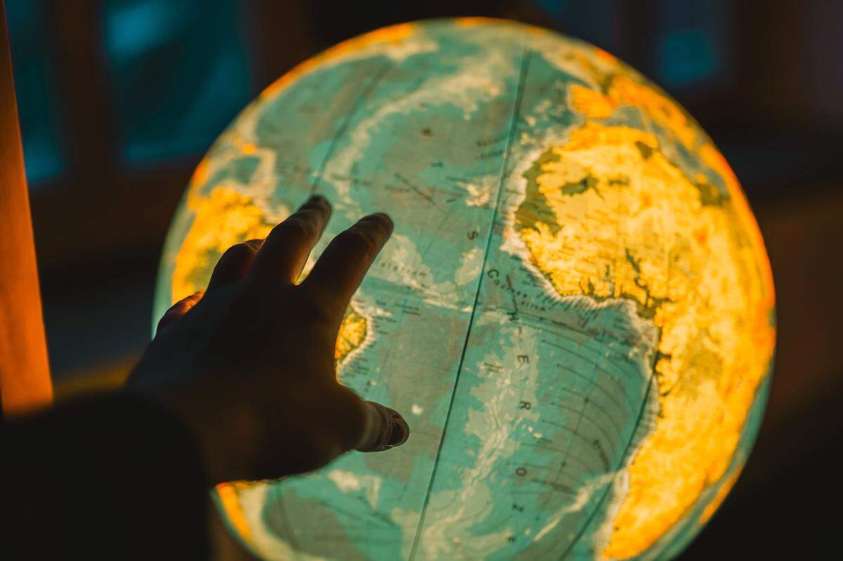 human hand touches lit globe