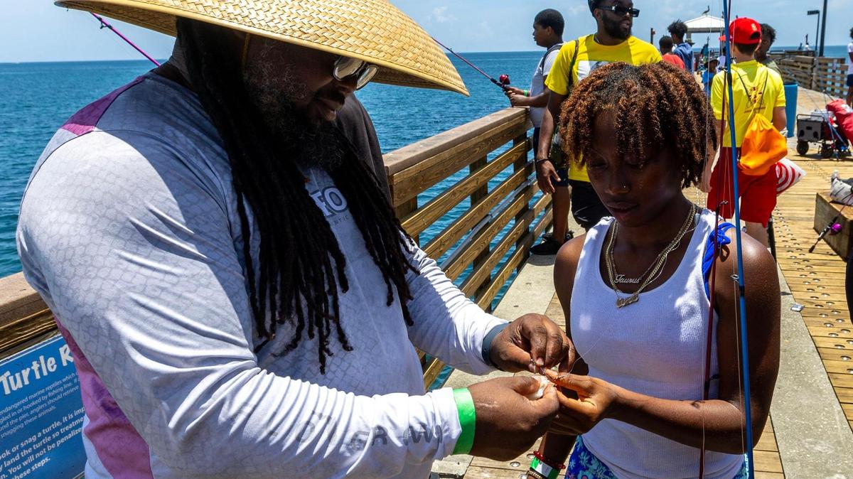 United and Unlimited mentor James Howard, 48, teaches Kimani Davis, 15, how to cut bait and rig a hook during a Root Collectives summer camp field trip at Dania Beach Pier in Dania Beach, Florida, on Wednesday, July 15, 2023.