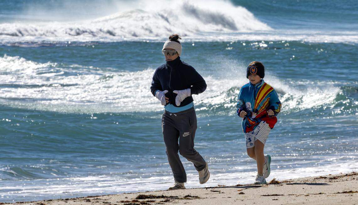 South Florida resident Stephanie DeFrancesco runs with her son, Ari Sella, as they bundle up against the cold on the beach in Sunny Isles Beach, Fla., Sunday, Feb. 1, 2026. Miami-area temperatures dipped into the 30s, the coldest in more than 15 years.