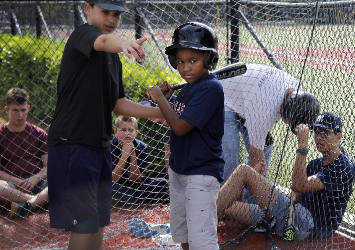 Noah Katzman, 14, instructs Garth Fowler, 9, on batting inside the batting cage while participating in North Miami Beach Little League’s Baseball Buddies program at Pelican Park in Sunny Isles Beach on Sunday, Nov. 4, 2018.