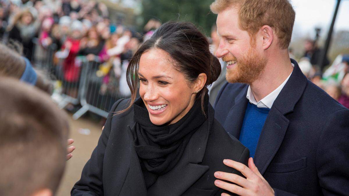 Prince Harry and Meghan Markle happily greet fans.
