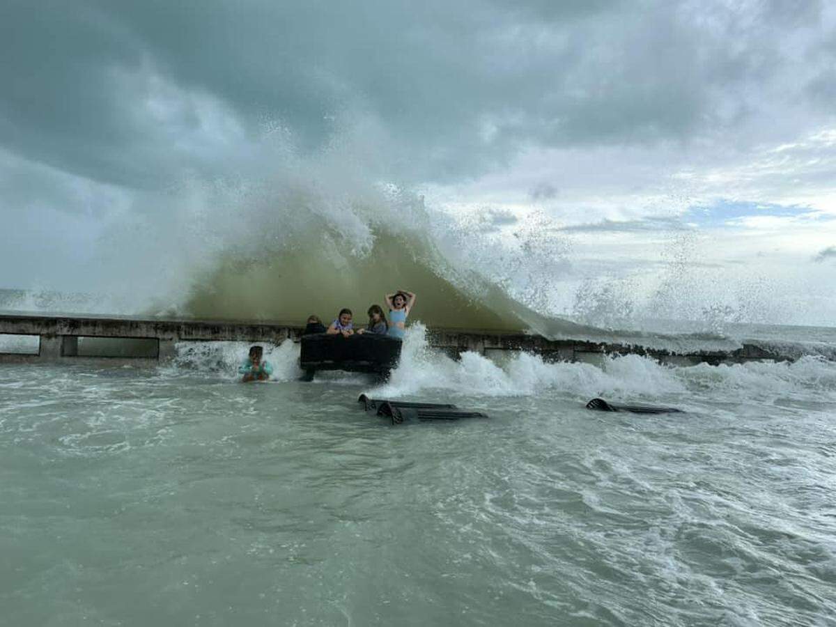 Children play on White Street Pier as they get splashed by a wave caused by Hurricane Helene storm surge Thursday, Sept. 26, 2024.