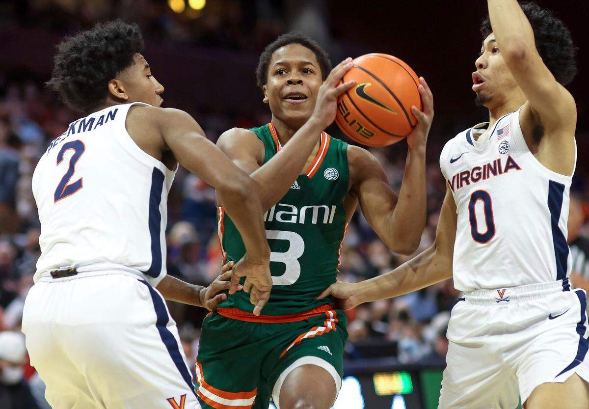 Miami guard Charlie Moore (3) moves between Virginia guards Reece Beekman (2) and Kihei Clark (0) during an NCAA college basketball game in Charlottesville, Va., Saturday, Feb. 5, 2022. (AP Photo/Andrew Shurtleff)