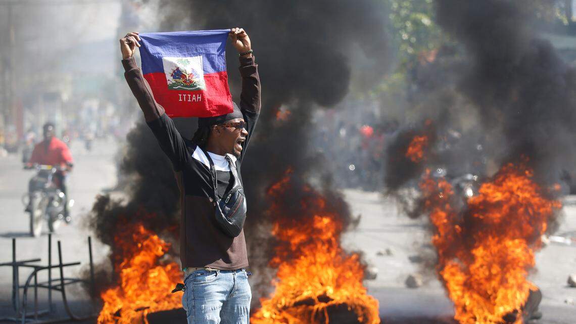 A demonstrator holds up a Haitian flag during protests demanding the resignation of Prime Minister Ariel Henry in Port-au-Prince, Haiti, Friday, March 1, 2024. (AP Photo/Odelyn Joseph)