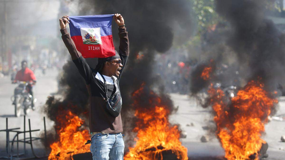 Un manifestante sostiene una bandera haitiana durante las protestas que exigen la renuncia del primer ministro Ariel Henry en Puerto Príncipe, Haití, el viernes 1 de marzo de 2024. (Foto AP/Odelyn Joseph)