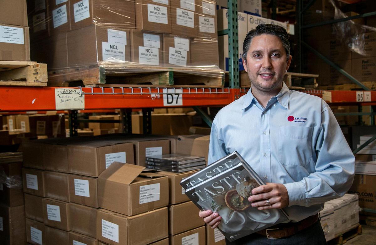 Ryan Schoeneck, Chief Operating Officer of J.M. Field Marketing, holds a couple of Crystal Cruises cookbooks that were produced during the pandemic. J.M. Field Marketing produces, packs and ships marketing material for the cruise industry.