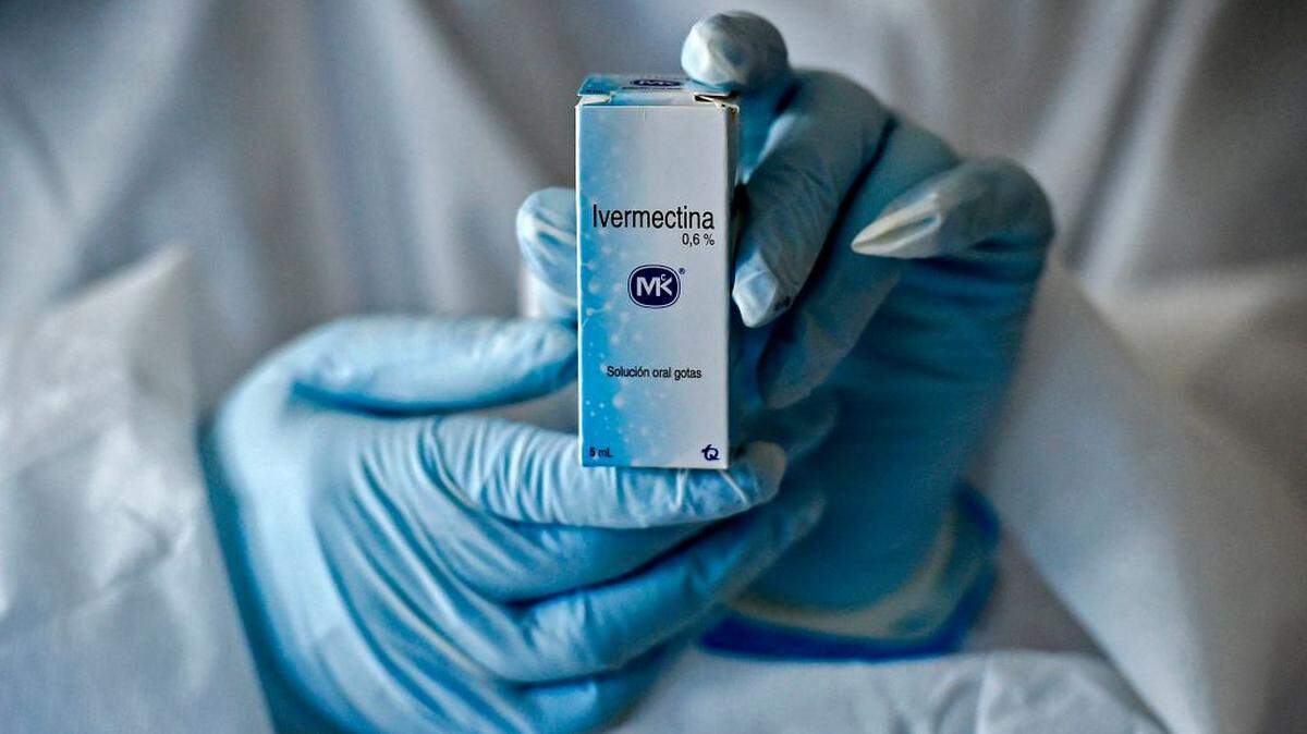 A health worker shows a box containing a bottle of ivermectin.