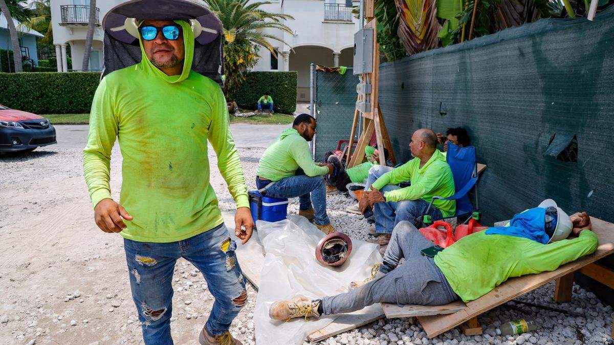 Elvin Murillo and fellow laborers wear protective gear against the hot sun as they take a break at a residential construction site on Key Biscayne, Florida, on May 17, 2024.