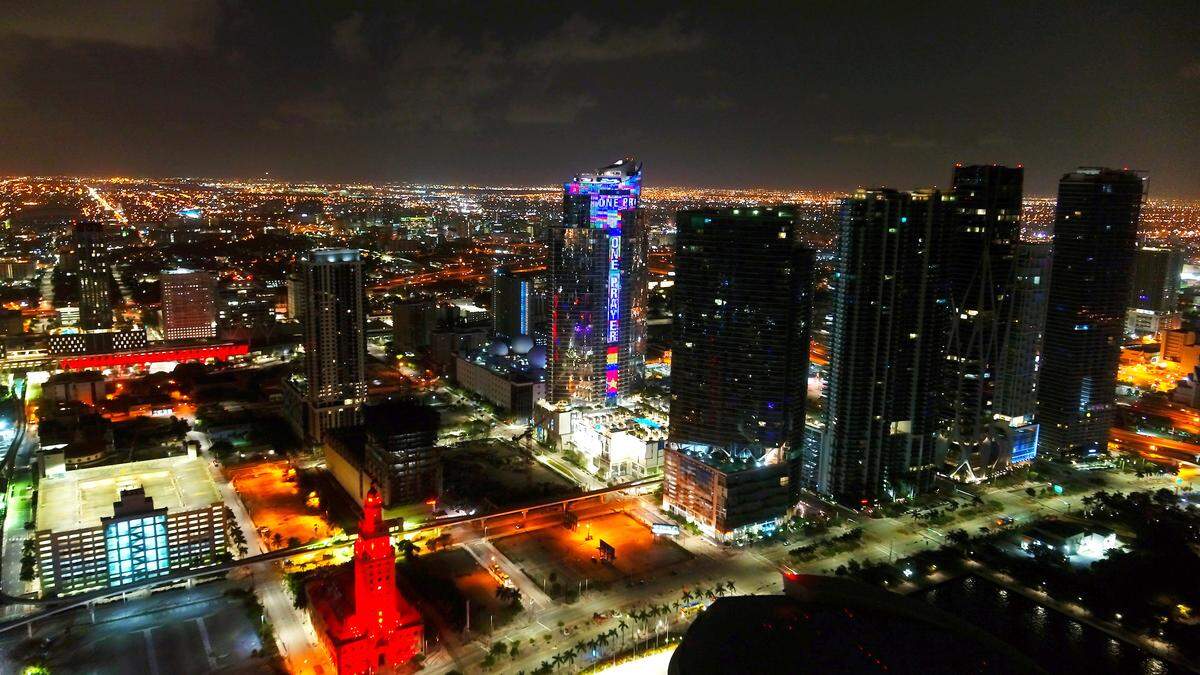 The 60-story Paramount Miami Worldcenter at 851 NE First Ave in Downtown Miami, will light up every night with hundreds of fluttering flags and the words “One World, One Prayer,” until all of the missing people in Surfside’s building collapse are found. Pictured above is a May 19, 2020 photo when the skyscraper was lit up during the week of the 39th annual funeral observance of music legend Bob Marley. (Bryan Glazer/World Satellite Television News via AP Images)